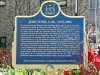 blue plaque with gold writing and crest of deers and a bear at the top