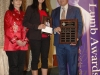 three people standing together holding awards