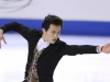 man figure skating with arms stretched out . Wearing balck jacket and vest for costume.