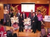 Sponsors on stage next to Chinese lion dancers with large colourful masks