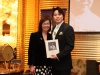two people standing together holding plaque with Jean Lumb's photo