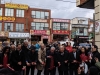 People standing in line for ceremonial ribbon cutting on crowded Chinatown street