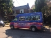 purple and red van with Jean Lumb poster on the window parked outside a home