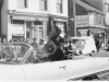 Jean Lumb sitting in back of converitble down busy pedestrian street in chinatown holding a megaphone.