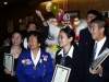Jean Lumb and several student posing in a group with awards next to chinese lion dancer in costume