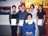 four student standing behind Jean Lumb holding their award plaques