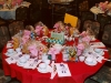 dinner table set with gift bags, white plates, red table cloth