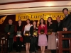 people grouped together onstage for a picture under Jean Lumb banner, four are holding their award plaques