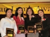four women standing together with their award plaques