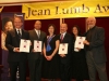 group of people posing for photo under Jean Lumb banner