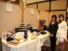long table with raffle prizes in gift bags or wrapping paper. two women standing next to table