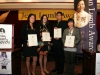 four award winners posing onstage with their award plaques