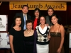 planning commitee smiling and posing for photo under Jean Lumb banner