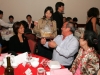 A raffle prize winner sitting at dinner table being given prize wrapped in bag
