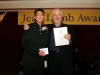 Two men posing for photo with awards in hand