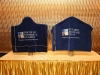 two large plaques standing on a table with gold table cloth. Plaques are covered by velvet fabric