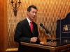 man with red tie is speaking at podium