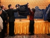 large plaques are placed on a table while two people remove their covers to unveil them