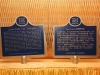 two plaques on table both are dark blue with gold border. one written in english and other in simplified chinese