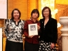 three women standing together person in center is holding Jean Lumb plaque