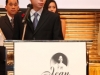 man standing at podium with a sign reading Jean Lumb awards