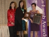 two award winners holding their plaques beside Jean Lumb banner