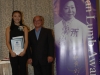 Two people standing together holding award.