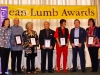 Volunteers holding Jean Lumb plaques under Jean Lumb Awards sign.
