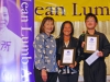 Three people posing for photo under Jean Lumb sign.