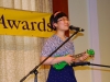 Musician playing green ukulele on stage.