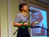 Musician playing green ukulele on stage.
