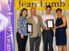 Four people standing together for photo under Jean Lumb sign.