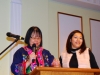 Two women speaking behind podium.
