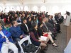 Large white tent with guest seated in rows for award ceremony.