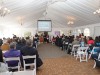 Large white tent with guest seated in rows for award ceremony.