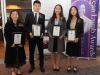four students holding their awards next to Jean Lumb banner.