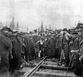 old photo with large crowd of working men standing around railway line