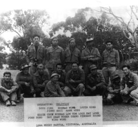 group of men in yard dressed in military wear kneeling and standing for group photo